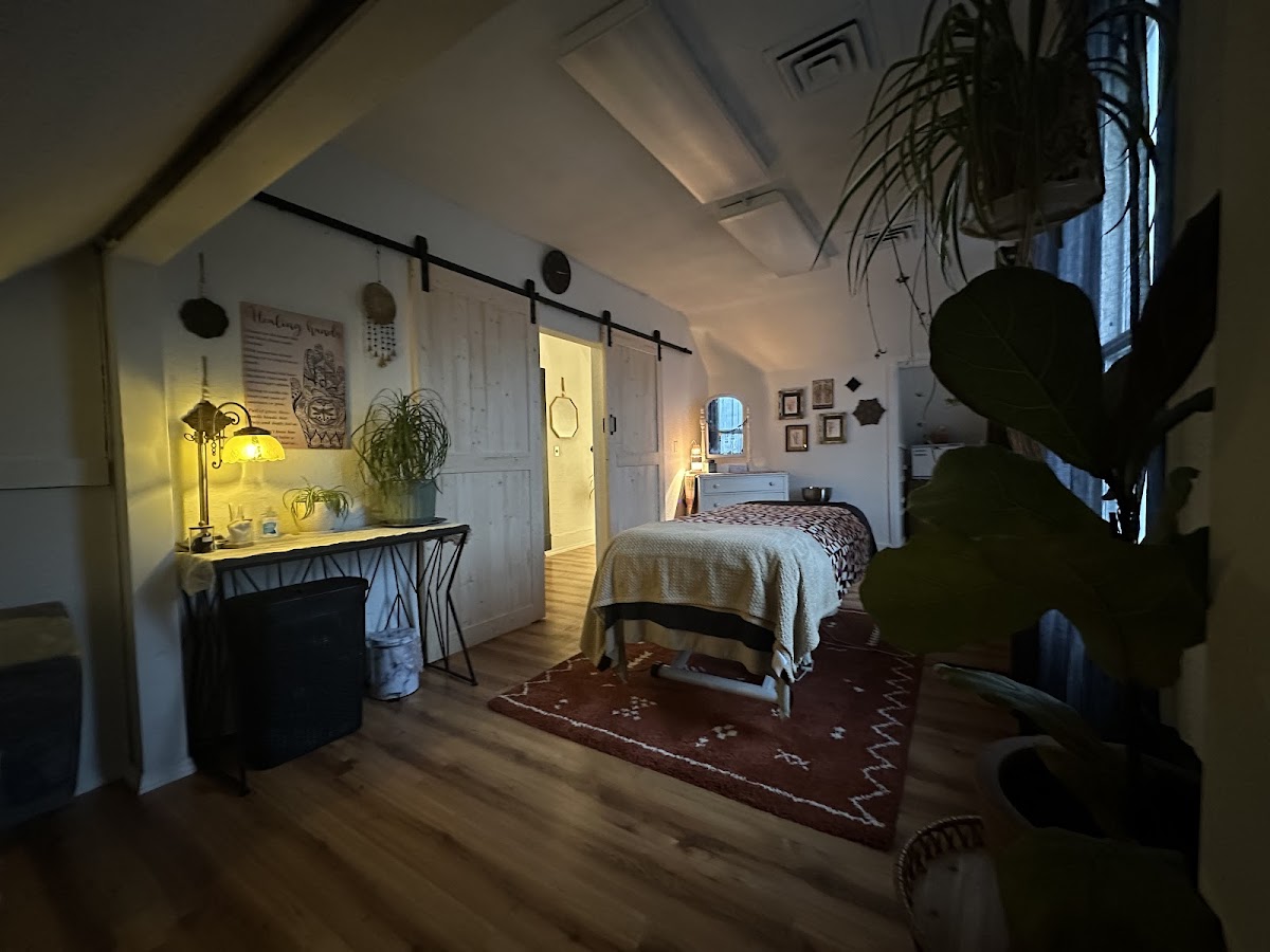 The candle-lit massage room at Wildflower, with a massage table, plants, and a terracotta rug
