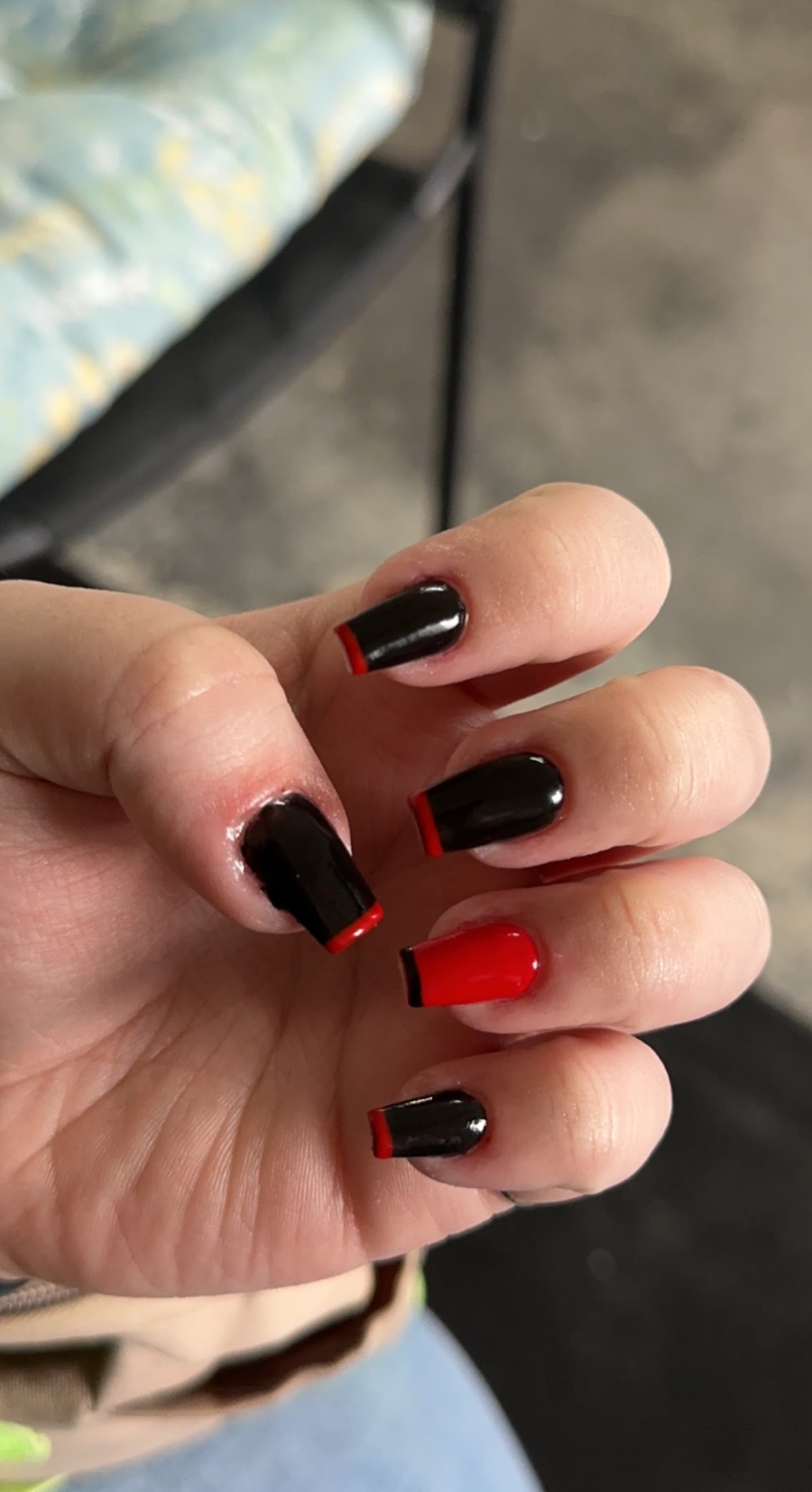 A finished manicure with a glossy black and red tip, done at Wildflower